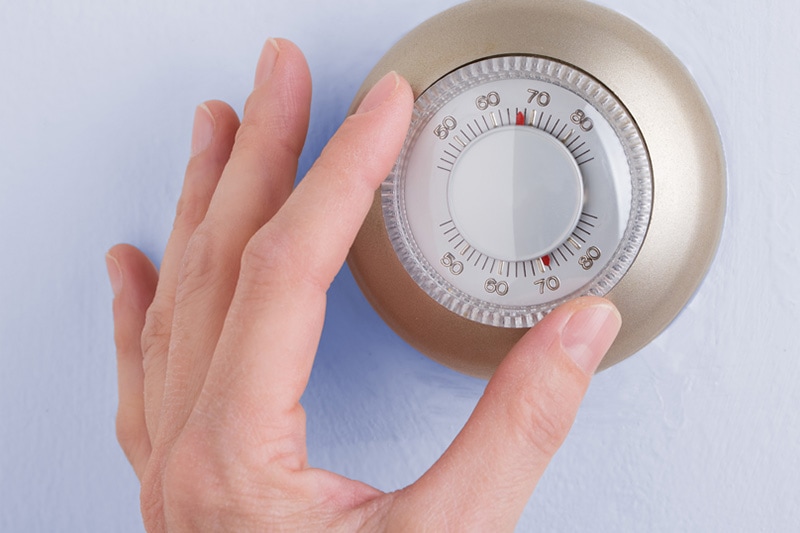 hand adjusting a thermostat.