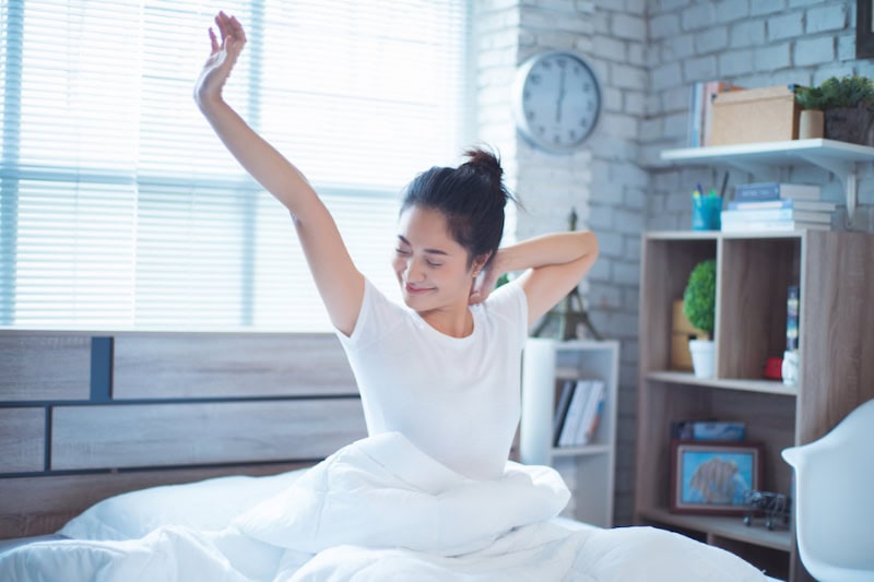 How Your HVAC System Can Help You Sleep. Photo of a woman waking in bed, stretching.