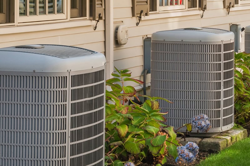 How to Determine the Perfect AC Size for Your Home. Photo of two AC units installed outside of a building.