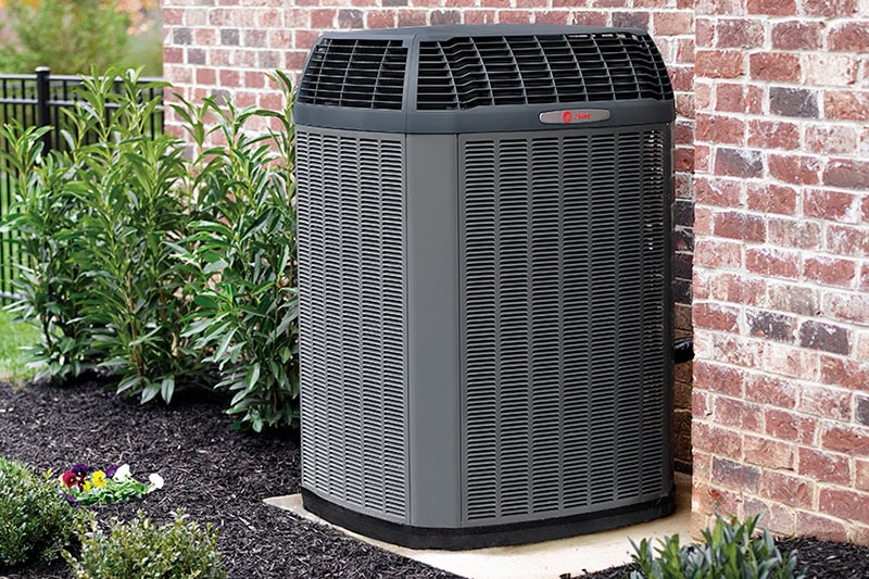 3 Tips to Prevent AC Breakdown During a Heat Wave. Photo of a black AC unit installed outside of a home or building.